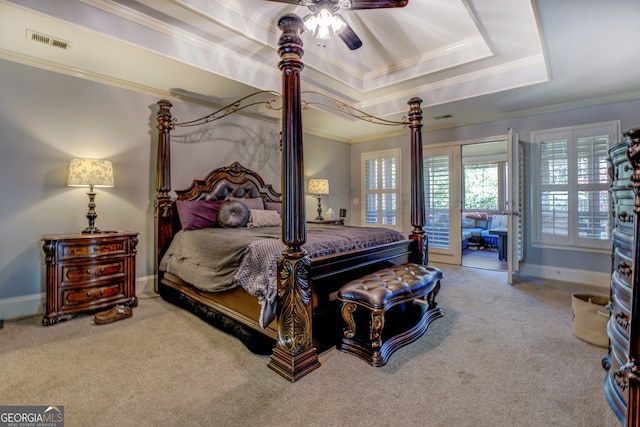 carpeted bedroom with a tray ceiling, ceiling fan, and crown molding