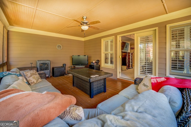 living room featuring crown molding, ceiling fan, wooden walls, and wood-type flooring