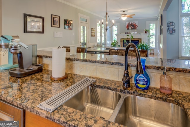 kitchen featuring decorative light fixtures, crown molding, sink, and a wealth of natural light