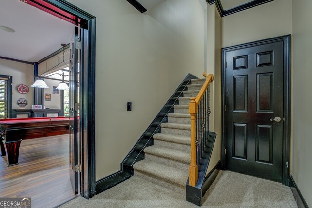 staircase featuring wood-type flooring, ornamental molding, and billiards