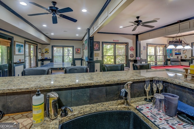 kitchen featuring light stone countertops, sink, ceiling fan, hanging light fixtures, and ornamental molding