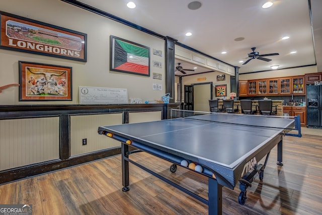 recreation room featuring bar, hardwood / wood-style flooring, and ceiling fan