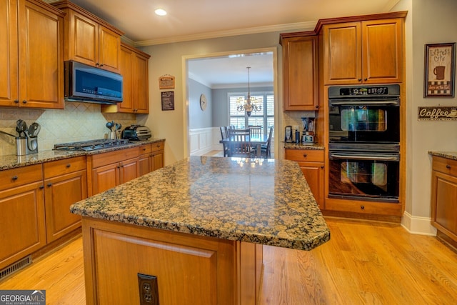 kitchen with a center island, stainless steel appliances, tasteful backsplash, light wood-type flooring, and ornamental molding