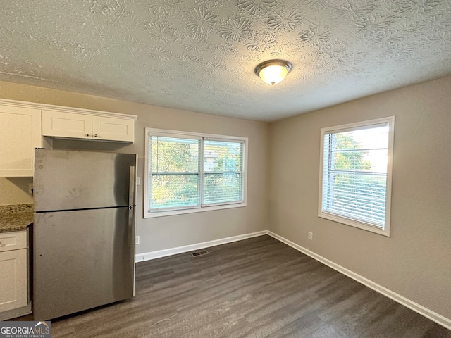 kitchen with white cabinets, stainless steel fridge, dark hardwood / wood-style flooring, and a textured ceiling