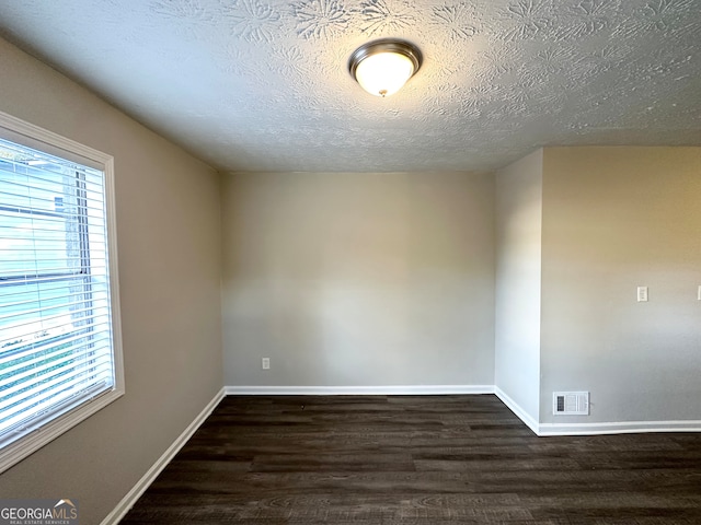 unfurnished room featuring dark hardwood / wood-style flooring and a textured ceiling