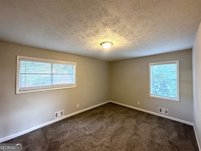 carpeted empty room with a textured ceiling