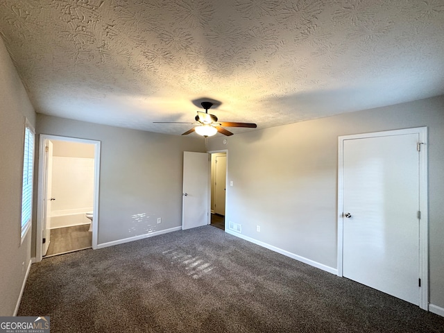 unfurnished bedroom featuring ensuite bath, ceiling fan, a textured ceiling, and dark colored carpet