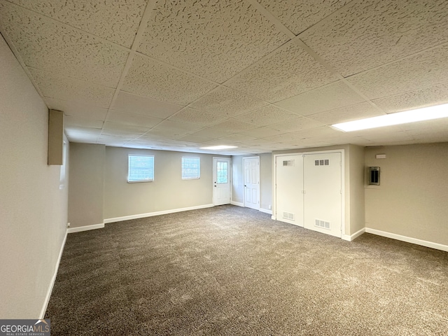 basement with a drop ceiling and dark carpet