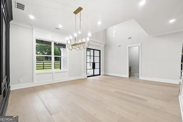 spare room with a notable chandelier, light wood-type flooring, and crown molding