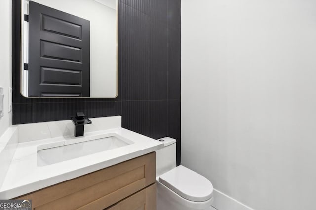 bathroom with vanity, tasteful backsplash, and toilet