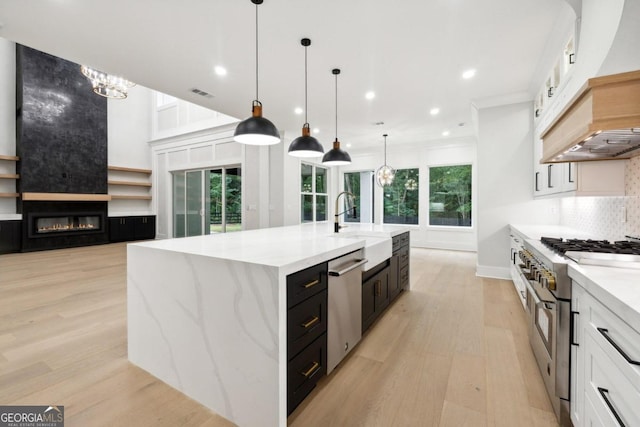 kitchen featuring decorative light fixtures, stainless steel appliances, white cabinetry, and a large island