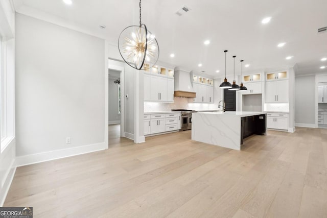 kitchen featuring high end range, an island with sink, light hardwood / wood-style floors, white cabinets, and custom exhaust hood