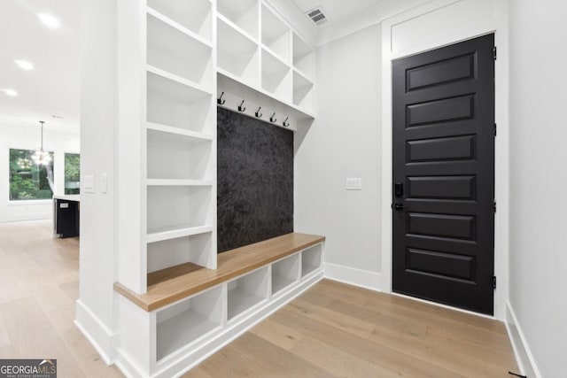 mudroom featuring light wood-type flooring and an inviting chandelier