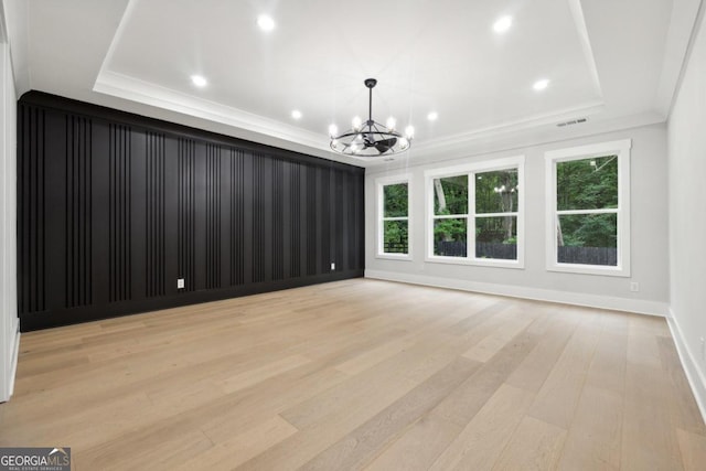 interior space featuring an inviting chandelier, a raised ceiling, and light hardwood / wood-style flooring