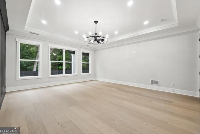 interior space featuring a tray ceiling, ornamental molding, light hardwood / wood-style floors, and a notable chandelier