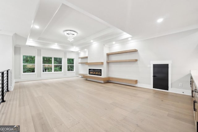 unfurnished living room featuring crown molding, a tray ceiling, and light hardwood / wood-style flooring