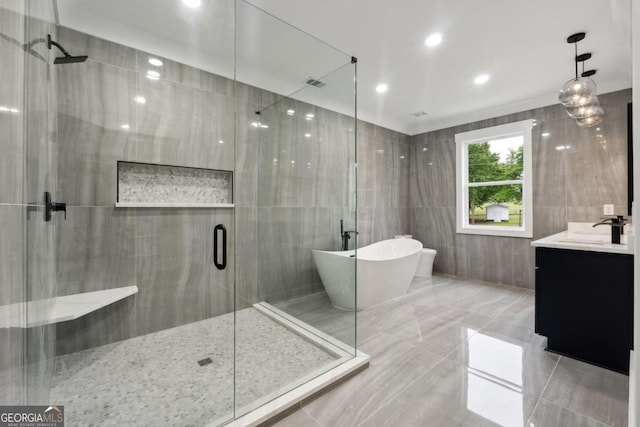 bathroom featuring vanity, tile walls, and independent shower and bath