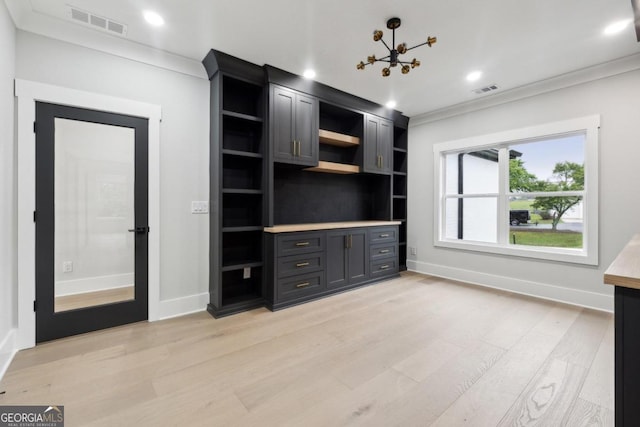 unfurnished office featuring a chandelier, light hardwood / wood-style floors, and ornamental molding