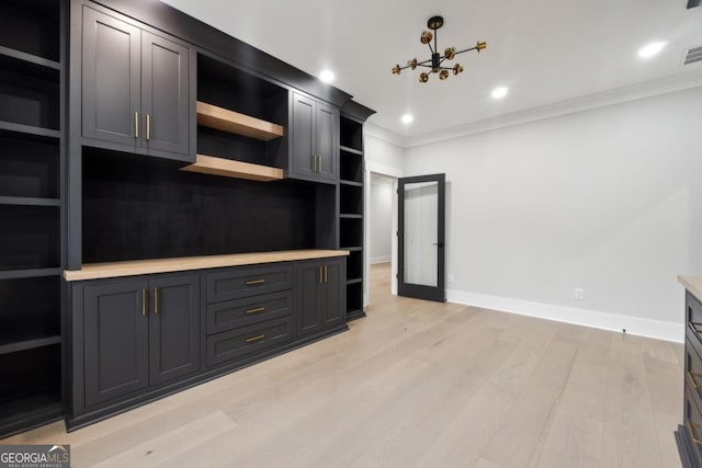 kitchen featuring light wood-type flooring, ornamental molding, and a notable chandelier