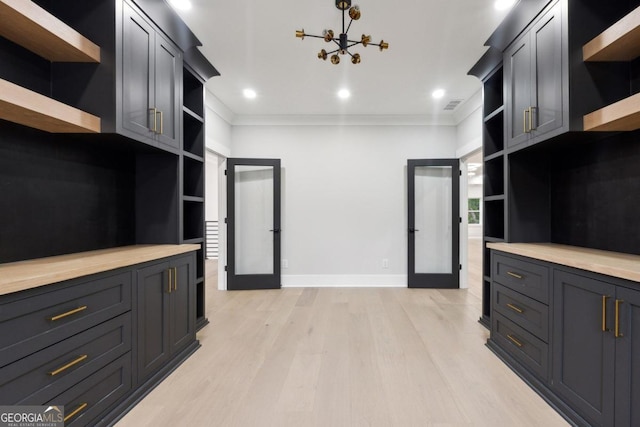 kitchen with wood counters, french doors, light hardwood / wood-style flooring, a notable chandelier, and hanging light fixtures