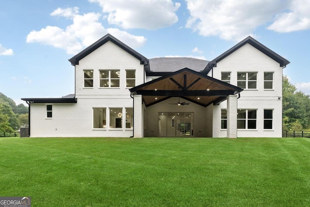 rear view of property featuring ceiling fan and a lawn