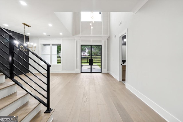 foyer featuring a chandelier, a high ceiling, and light wood-type flooring