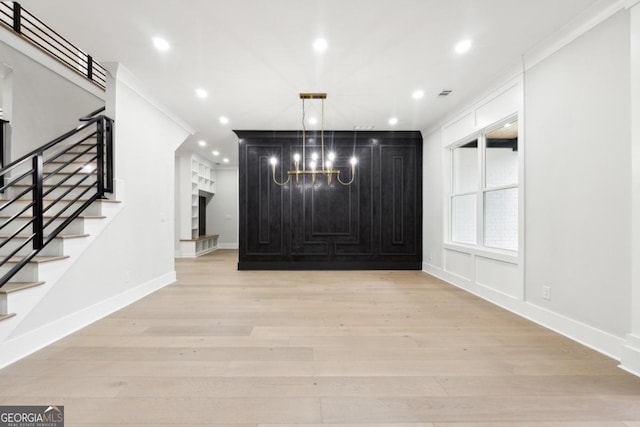 entrance foyer with ornamental molding, light hardwood / wood-style floors, and an inviting chandelier