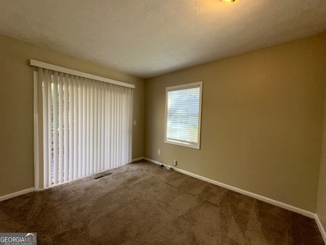 spare room featuring carpet and a textured ceiling