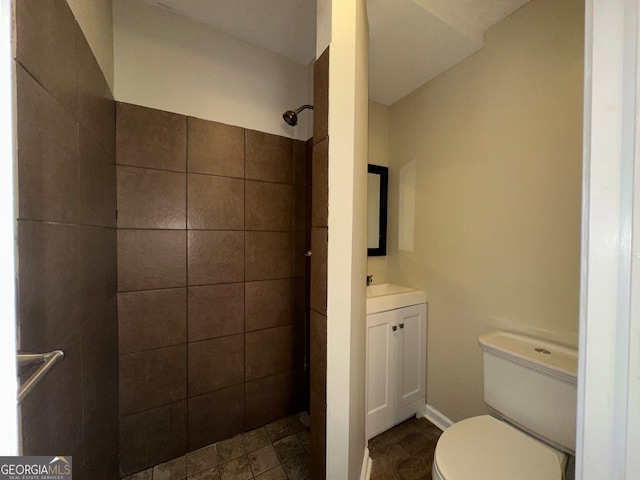 bathroom with a tile shower, vanity, toilet, and tile patterned floors