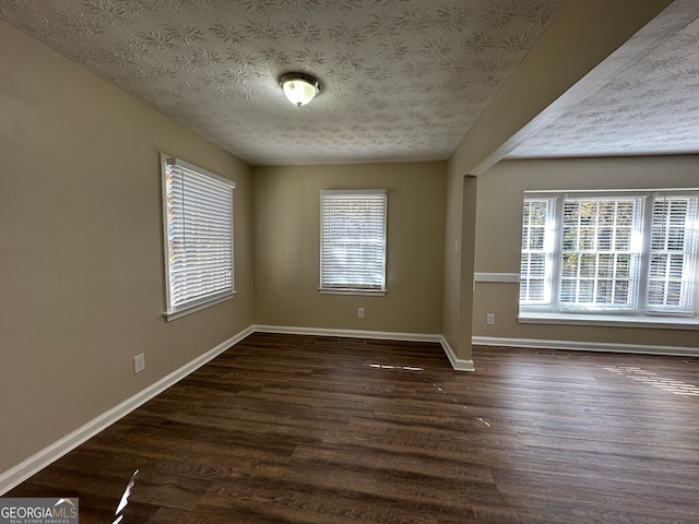 spare room with dark hardwood / wood-style floors and a textured ceiling