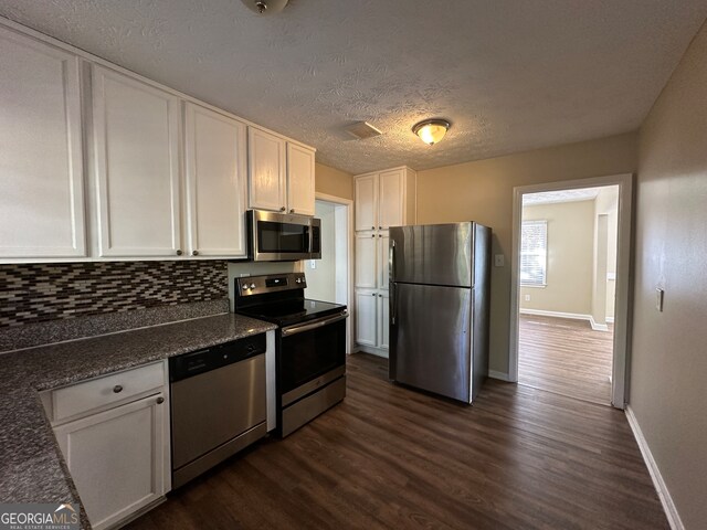 kitchen featuring appliances with stainless steel finishes, tasteful backsplash, a textured ceiling, dark wood-type flooring, and white cabinetry