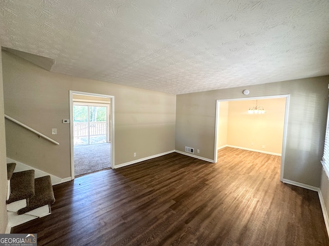 unfurnished room with wood-type flooring, a textured ceiling, and a notable chandelier