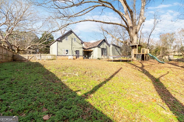 rear view of house featuring a playground, a yard, and a trampoline