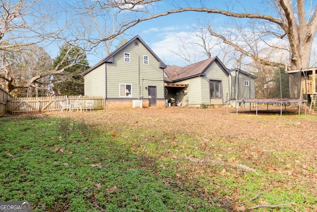 rear view of house with a lawn and a trampoline