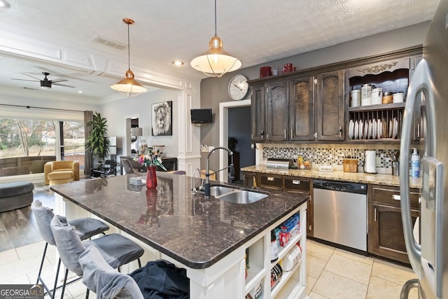 kitchen featuring dark brown cabinetry, stainless steel appliances, ceiling fan, sink, and decorative light fixtures