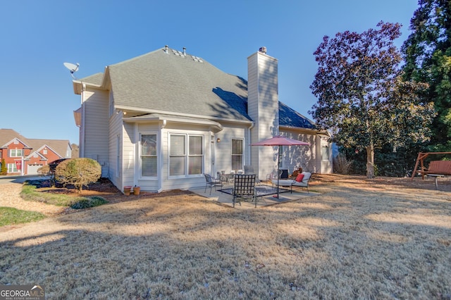 rear view of property with a yard, a shingled roof, a chimney, and a patio