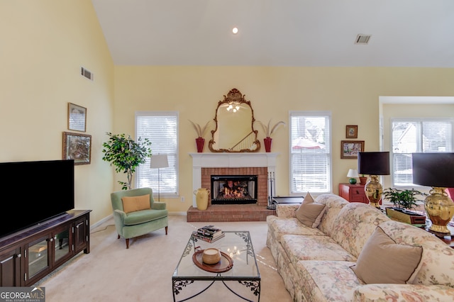 living area with light carpet, a brick fireplace, visible vents, and vaulted ceiling