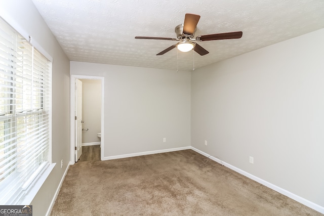 carpeted spare room featuring ceiling fan and a textured ceiling