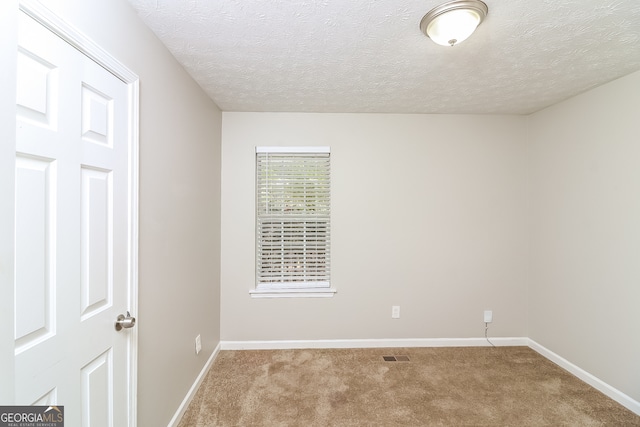 carpeted spare room with a textured ceiling