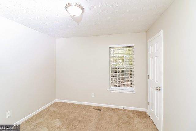 carpeted empty room with a textured ceiling