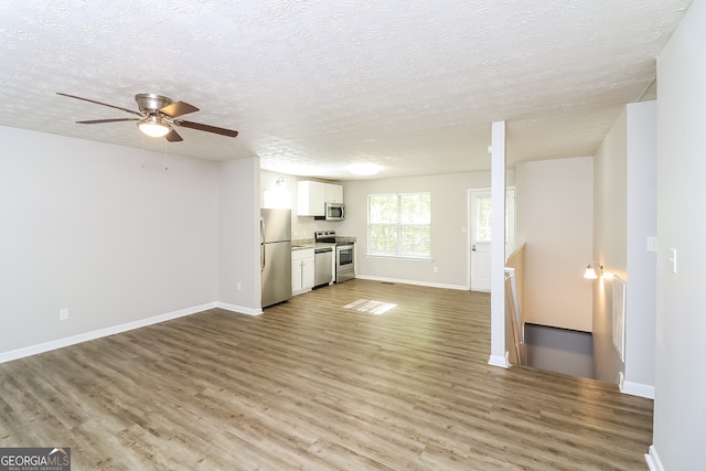 unfurnished living room featuring a textured ceiling, light hardwood / wood-style floors, and ceiling fan