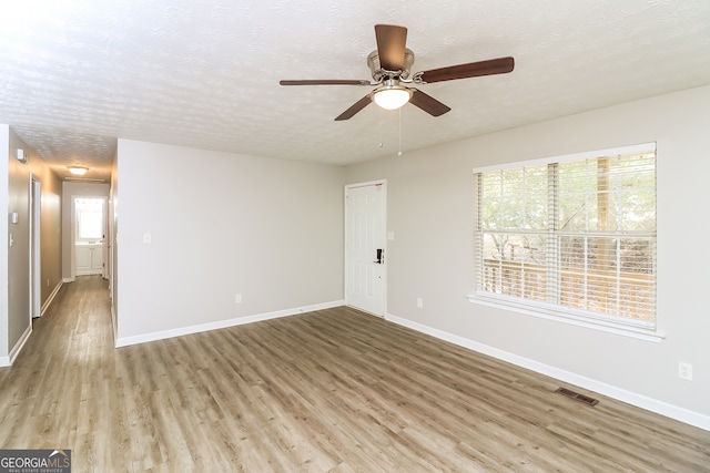 empty room featuring ceiling fan, light hardwood / wood-style flooring, and a textured ceiling