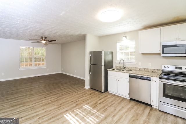 kitchen featuring plenty of natural light, white cabinets, stainless steel appliances, and light hardwood / wood-style floors