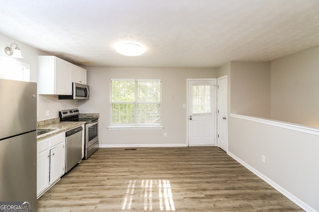 kitchen with appliances with stainless steel finishes, light wood-type flooring, and white cabinetry