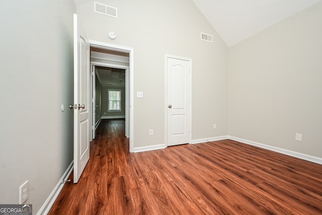 spare room with dark hardwood / wood-style flooring and high vaulted ceiling