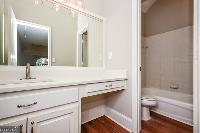 full bathroom featuring vanity, wood-type flooring, tiled shower / bath combo, and toilet