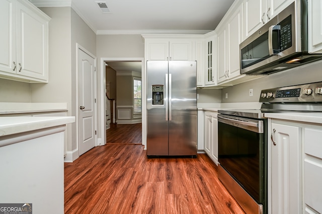 kitchen featuring white cabinetry, dark hardwood / wood-style flooring, ornamental molding, and appliances with stainless steel finishes