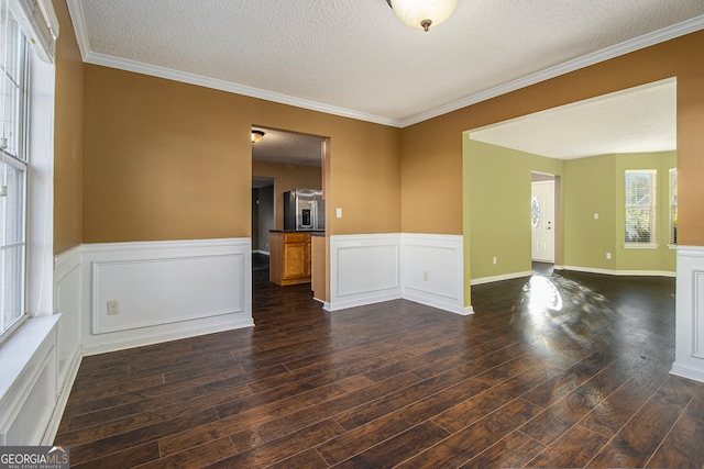 empty room featuring dark hardwood / wood-style floors, ornamental molding, and a textured ceiling