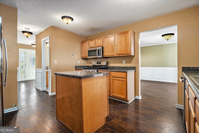 kitchen featuring a textured ceiling, a center island, stainless steel appliances, and dark wood-type flooring