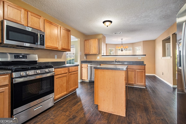 kitchen featuring stainless steel appliances, dark wood-type flooring, decorative light fixtures, an inviting chandelier, and a center island